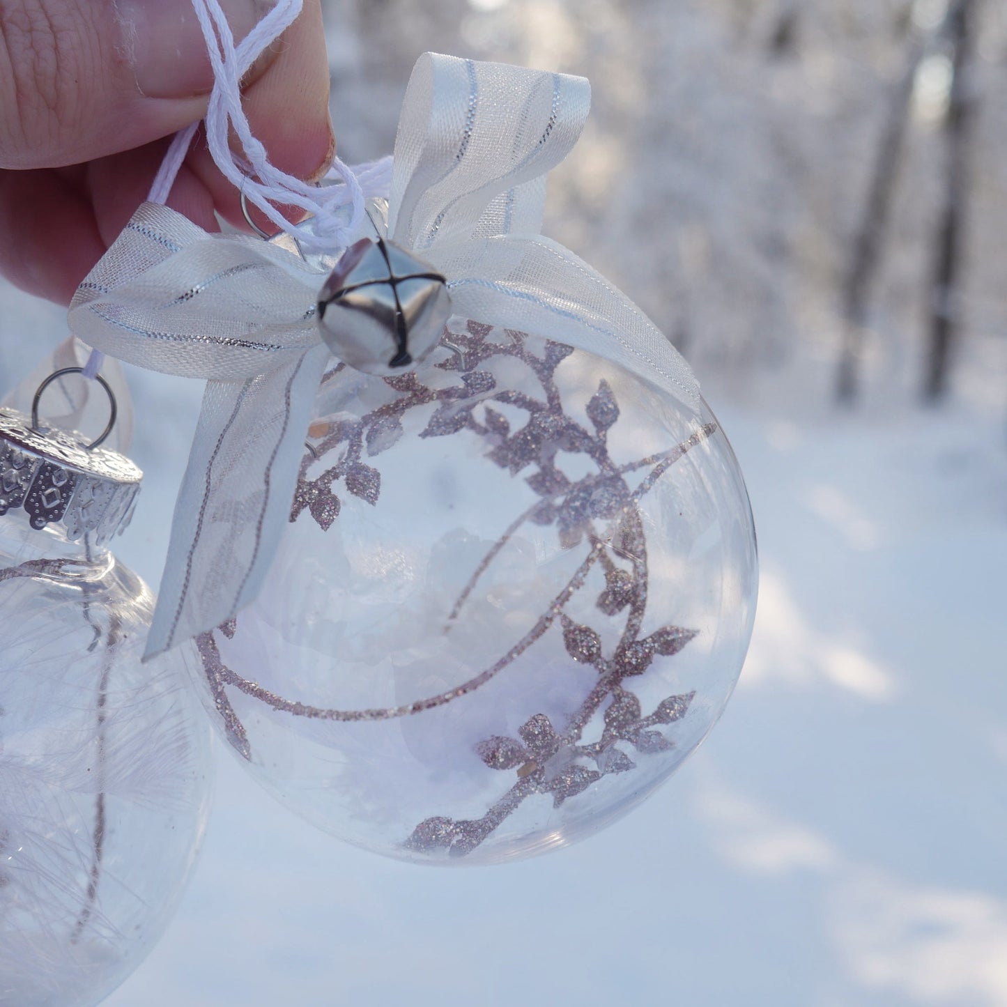 duo de boules en plastiques contenant une plume et diverses décorations roses
