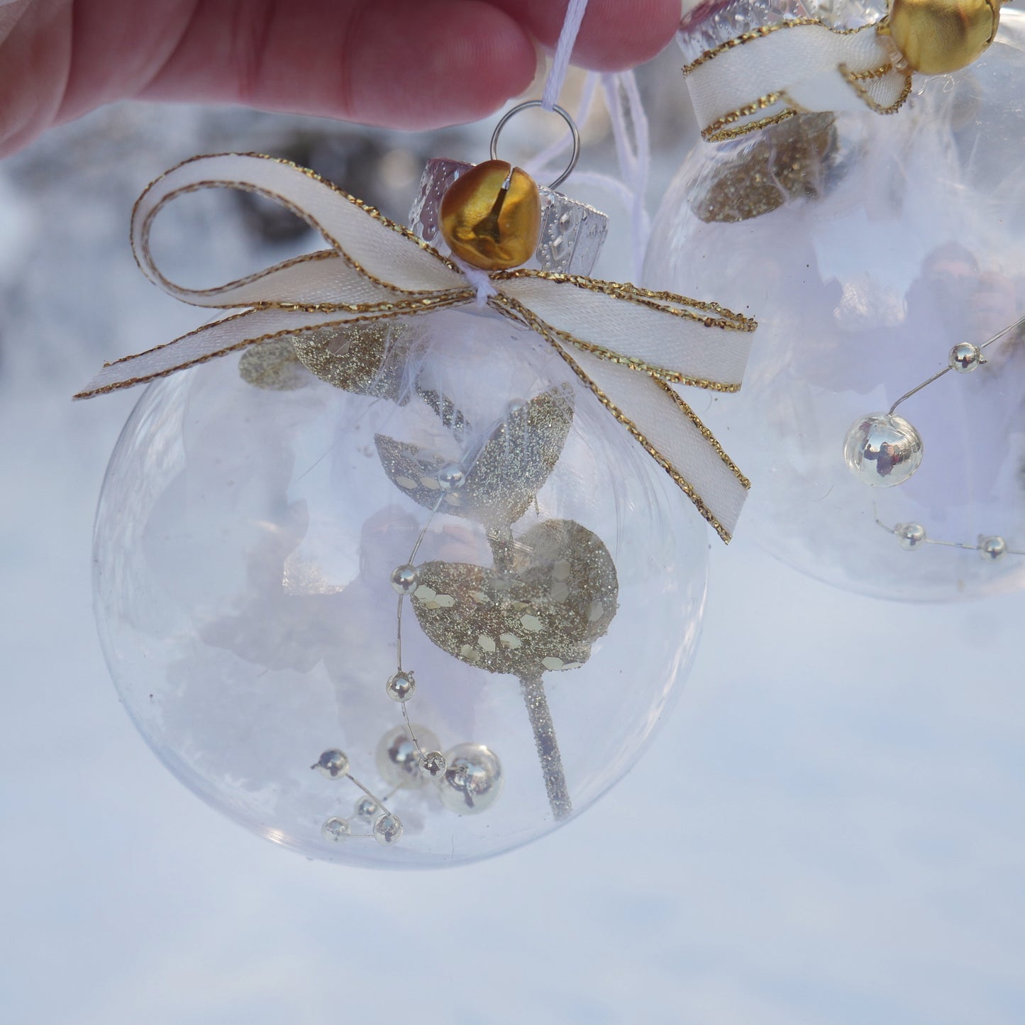 duo de boules en plastiques contenant une plume et diverses décorations dorées