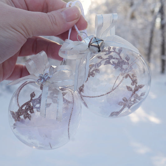 duo de boules en plastiques contenant une plume et diverses décorations roses