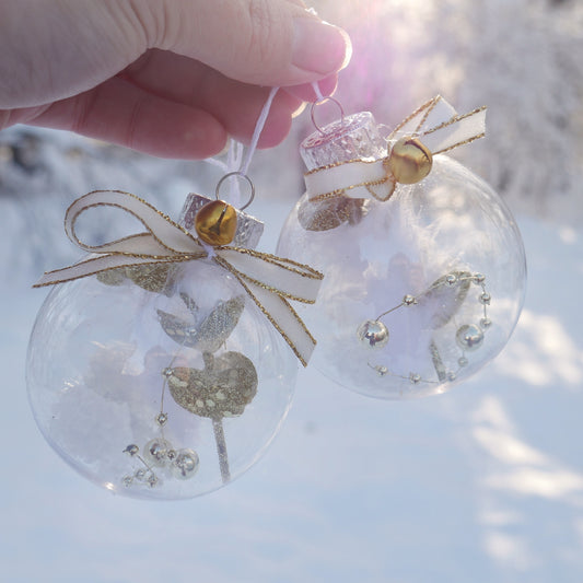 duo de boules en plastiques contenant une plume et diverses décorations dorées