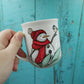 Petite tasse bonhomme de neige avec tuque et foulard rouge