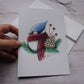 Carte de vœux geai bleu avec foulard rouge et branches de sapin