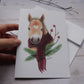 Carte de vœux cheval blond avec foulard rouge et branches de sapin
