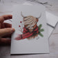 Carte de vœux vache highland avec foulard rouge et branches de sapin